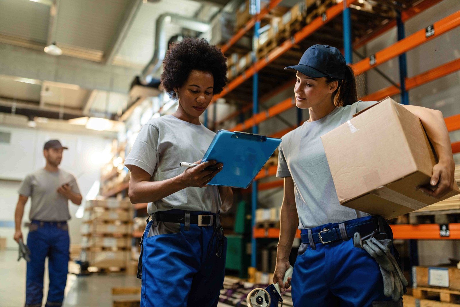 low angle view two female workers reading delivery schedule list while working distribution warehouse